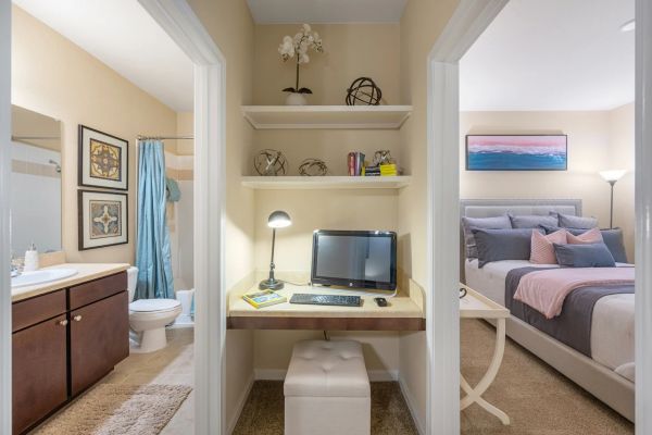 Integra Woods A small home office nook with a computer between a bathroom and a bedroom with pink and blue decor.